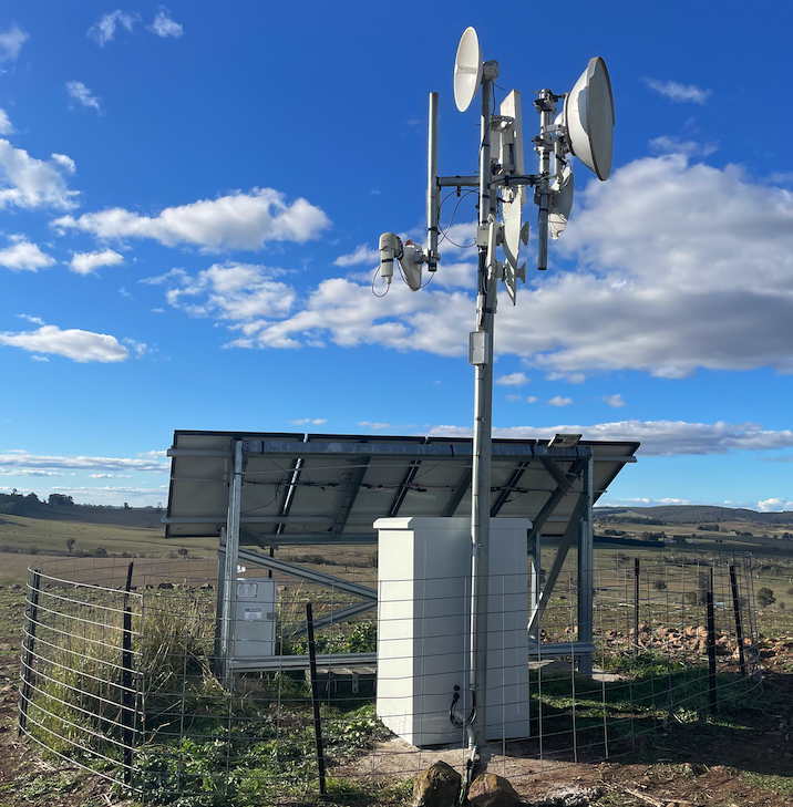 Solar-powered rural wireless tower with multiple dishes on a farm