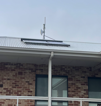 Roof-mounted wireless antenna on a brick farmhouse